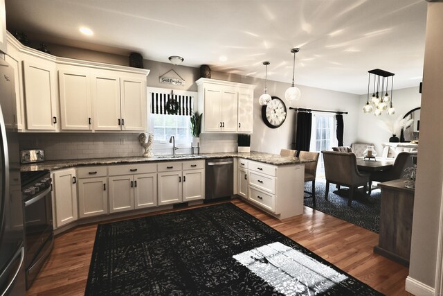 kitchen featuring stainless steel appliances, dark wood-type flooring, a peninsula, a sink, and recessed lighting