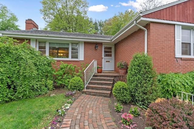 doorway to property with brick siding and a chimney