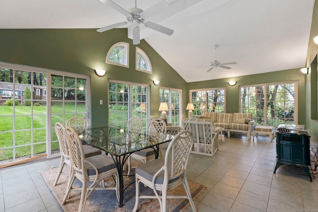 sunroom with a wood stove, high vaulted ceiling, tile patterned floors, and healthy amount of natural light
