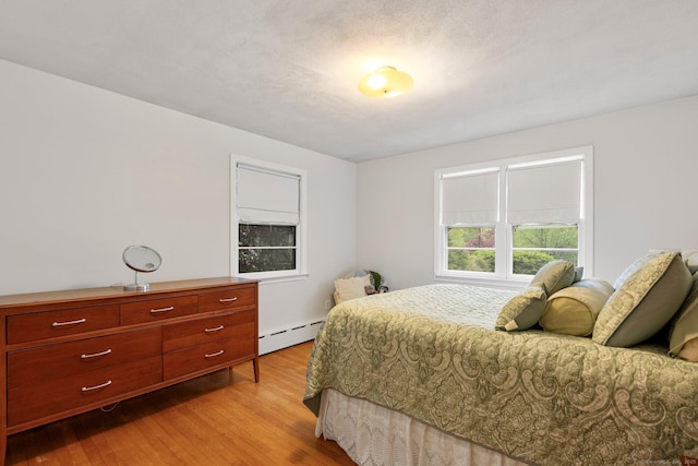 bedroom with baseboard heating and light wood-style floors