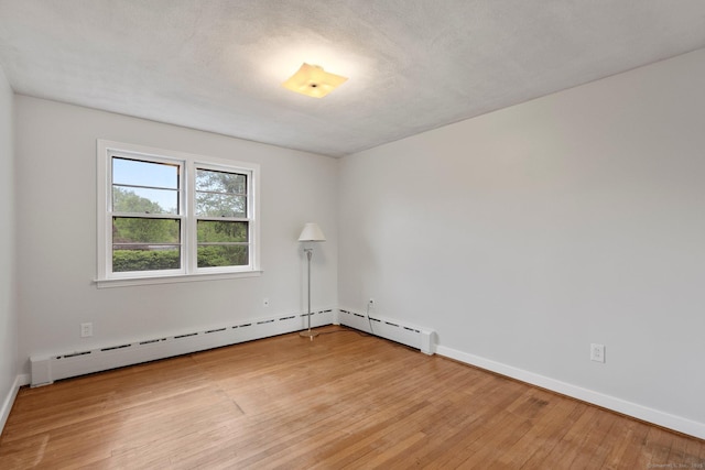 spare room with light wood-style floors, baseboards, and baseboard heating
