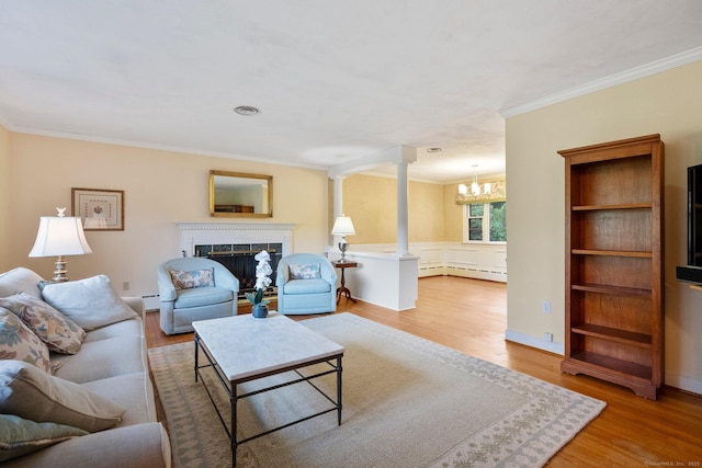 living area featuring crown molding, a chandelier, wood finished floors, decorative columns, and a premium fireplace
