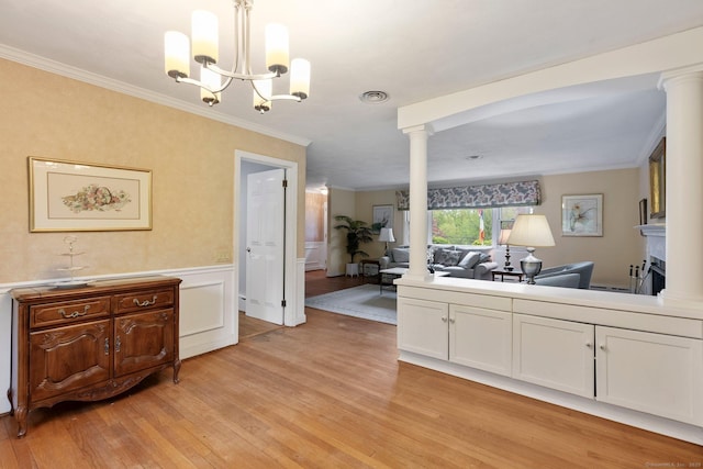 kitchen featuring light wood finished floors, open floor plan, white cabinets, ornamental molding, and decorative columns