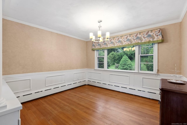 unfurnished dining area with a chandelier, light wood finished floors, ornamental molding, a wainscoted wall, and a decorative wall