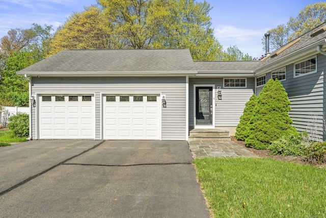 ranch-style house featuring asphalt driveway, a garage, and roof with shingles