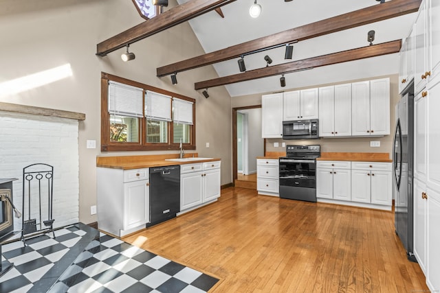 kitchen with stainless steel appliances, a sink, rail lighting, beamed ceiling, and high vaulted ceiling
