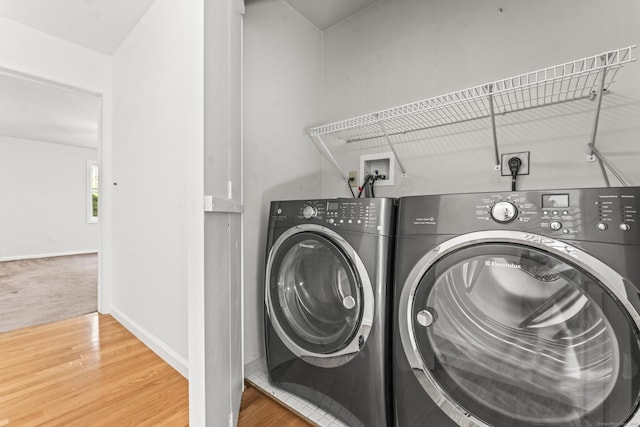 washroom featuring washer and dryer, wood finished floors, and baseboards