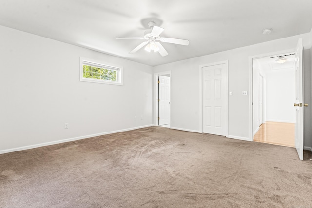 unfurnished bedroom featuring carpet, baseboards, attic access, and a ceiling fan