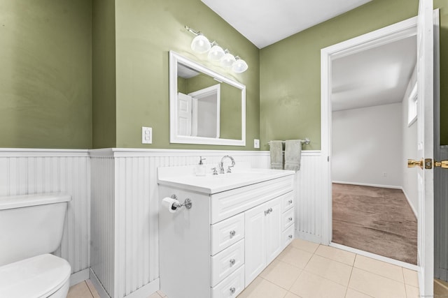 bathroom with toilet, a wainscoted wall, tile patterned floors, and vanity