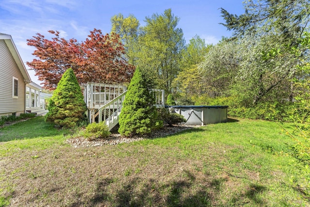 view of grassy yard with a covered pool, a deck, and stairway