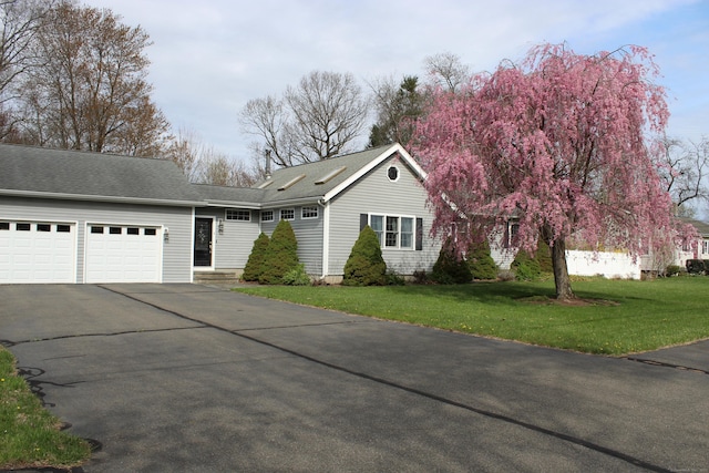 view of front of home featuring driveway, an attached garage, a front yard, and a shingled roof