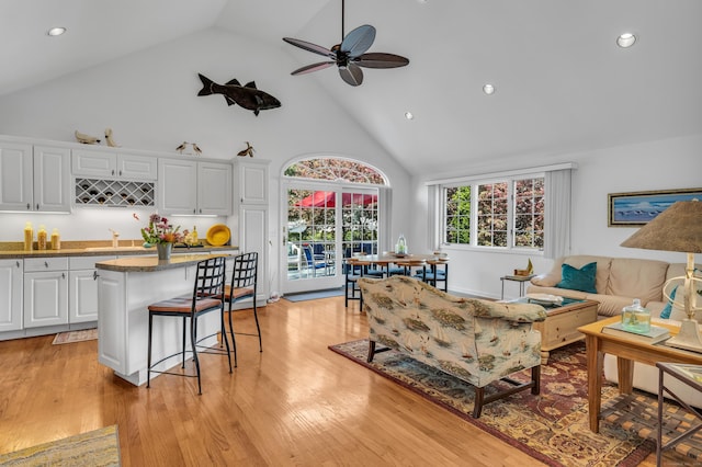 living area featuring high vaulted ceiling, recessed lighting, a ceiling fan, light wood-style floors, and bar with sink