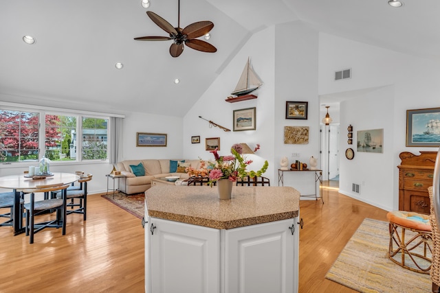 kitchen with ceiling fan, white cabinetry, high vaulted ceiling, light wood-style floors, and a center island