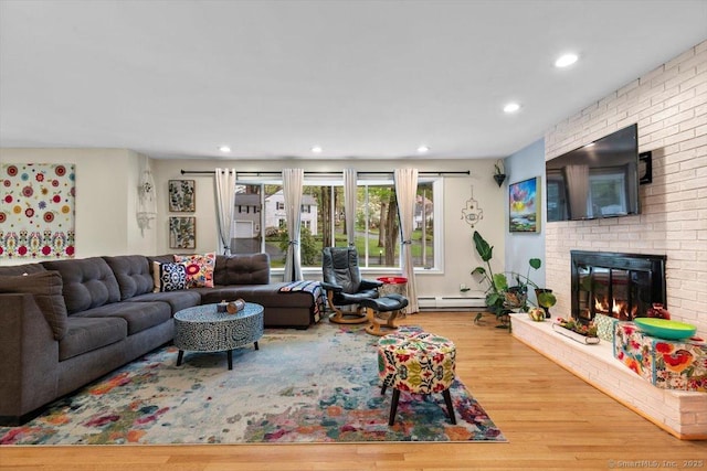 living area with a baseboard heating unit, a brick fireplace, recessed lighting, and wood finished floors