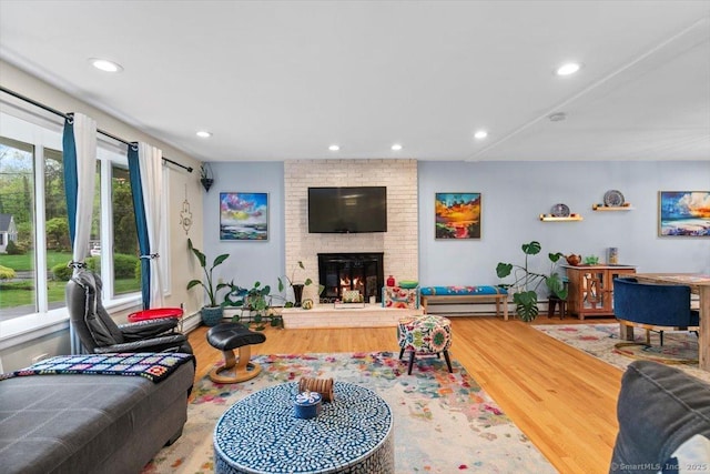 living room featuring recessed lighting, a brick fireplace, and wood finished floors
