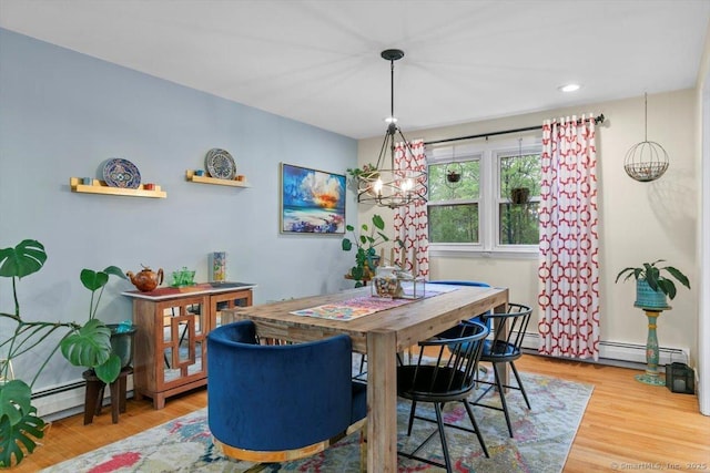 dining room featuring a baseboard heating unit, an inviting chandelier, and wood finished floors