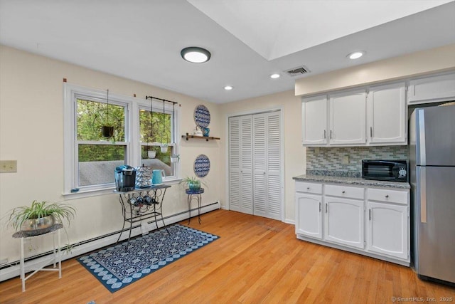 kitchen with freestanding refrigerator, light wood-style floors, white cabinets, and a baseboard heating unit
