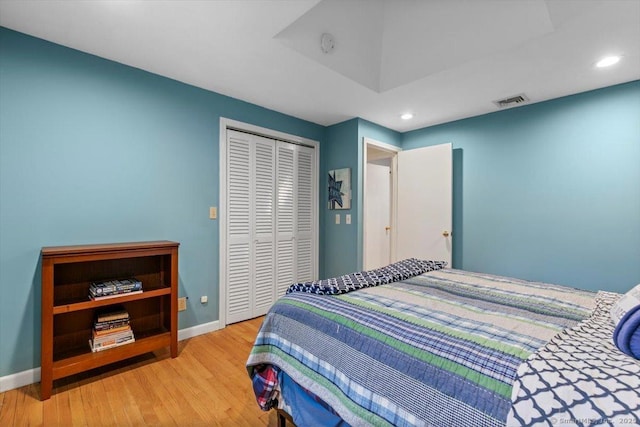 bedroom with a closet, recessed lighting, baseboards, visible vents, and wood finished floors