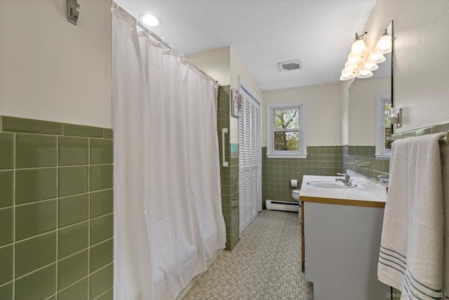 bathroom with tile walls, vanity, visible vents, tile patterned floors, and wainscoting