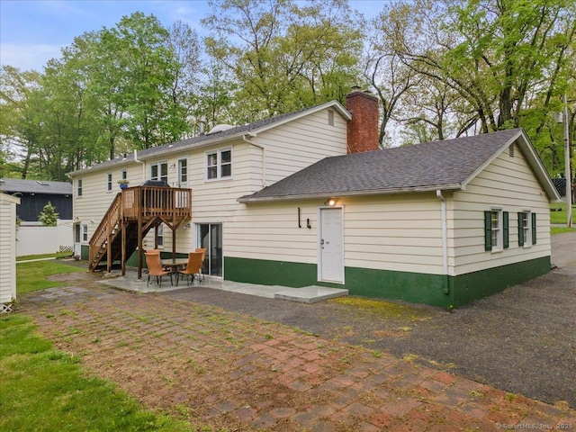 back of property featuring a patio area, a deck, stairway, a chimney, and a shingled roof