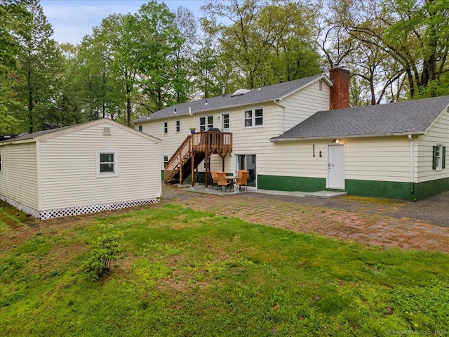back of property with a patio, stairway, a wooden deck, a chimney, and a lawn