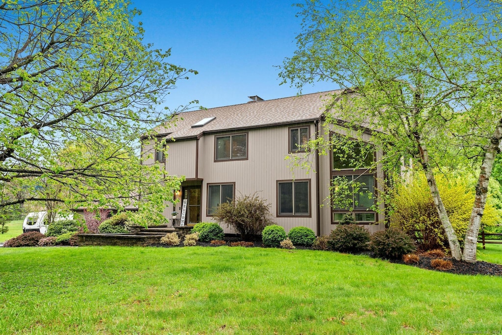 view of front of property featuring a shingled roof and a front yard