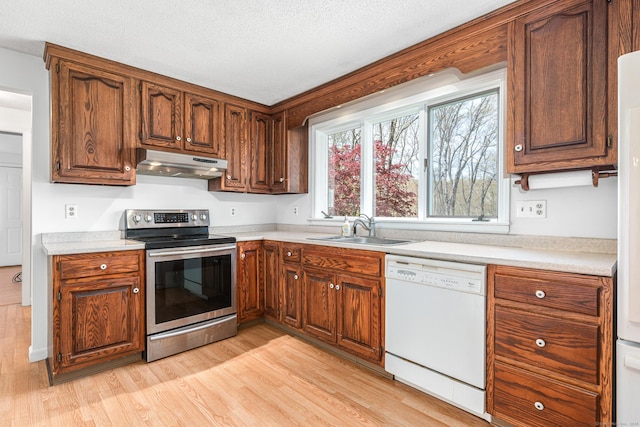 kitchen featuring electric range, dishwasher, under cabinet range hood, a sink, and light wood-type flooring