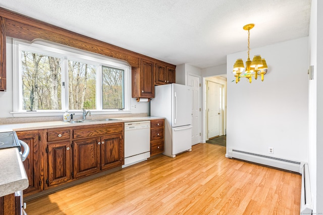 kitchen featuring white appliances, a sink, baseboard heating, a chandelier, and light wood-type flooring