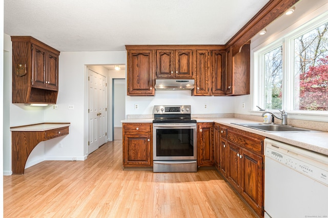 kitchen with electric range, white dishwasher, under cabinet range hood, a sink, and light wood-style flooring