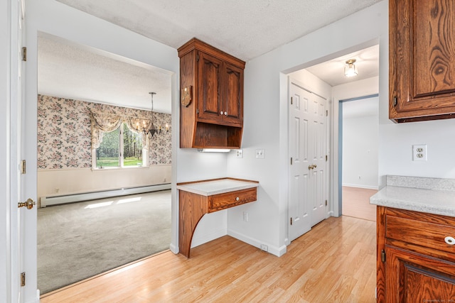 kitchen with a baseboard radiator, light wood-style flooring, a chandelier, light countertops, and brown cabinetry