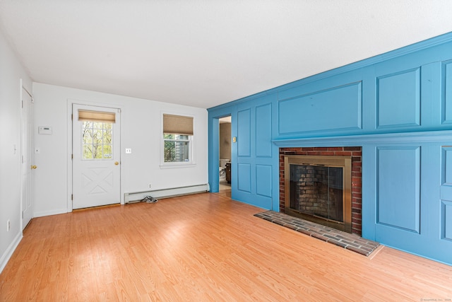 unfurnished living room featuring baseboard heating, a brick fireplace, light wood-style flooring, and baseboards
