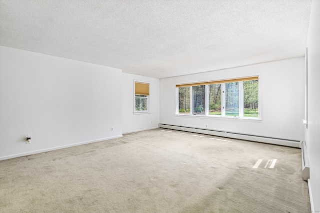 spare room featuring baseboard heating, a textured ceiling, carpet flooring, and baseboards