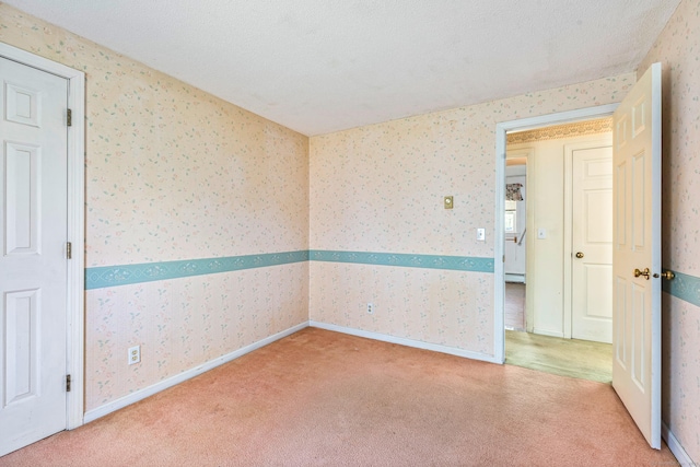 carpeted empty room featuring wallpapered walls and baseboards