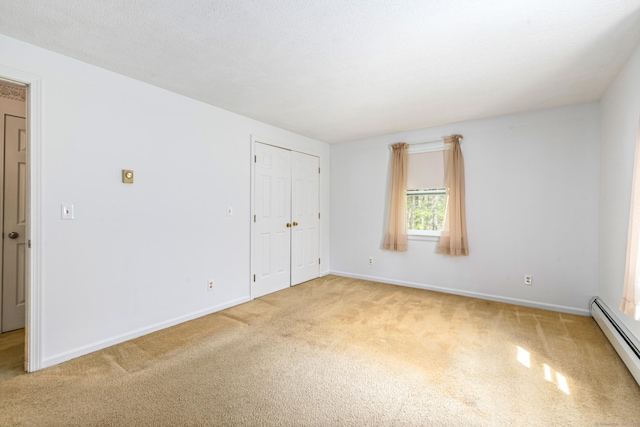 spare room with baseboard heating, light carpet, and baseboards