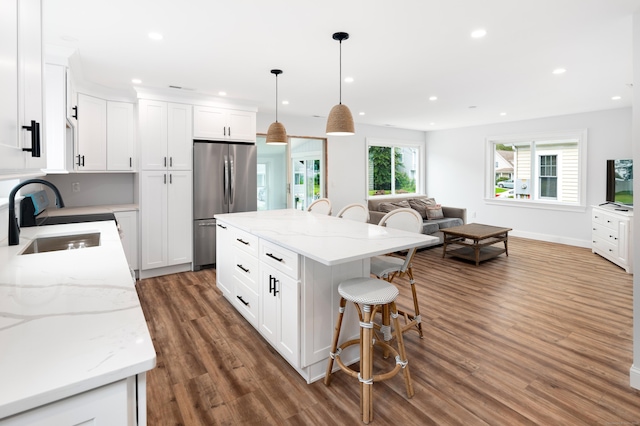 24 Sea Crest Ave, East Lyme, CT 06357 - kitchen with a sink, stainless steel fridge, a kitchen bar, wood finished floors, and white cabinets