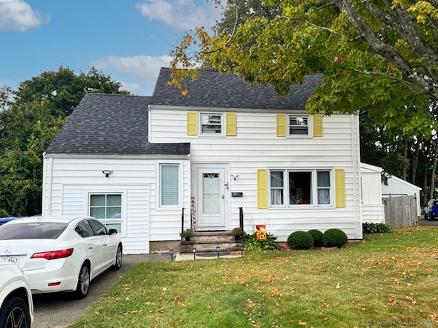 view of front of home featuring a front yard and roof with shingles
