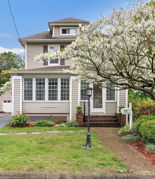 view of front of home featuring a front yard, a garage, a shingled roof, and entry steps