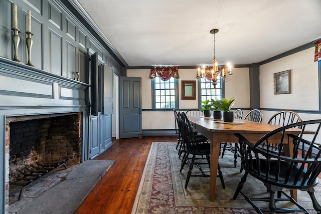 1696 Main St, Glastonbury, CT 06033 - dining area featuring dark wood-style flooring, ornamental molding, a notable chandelier, and a fireplace with raised hearth