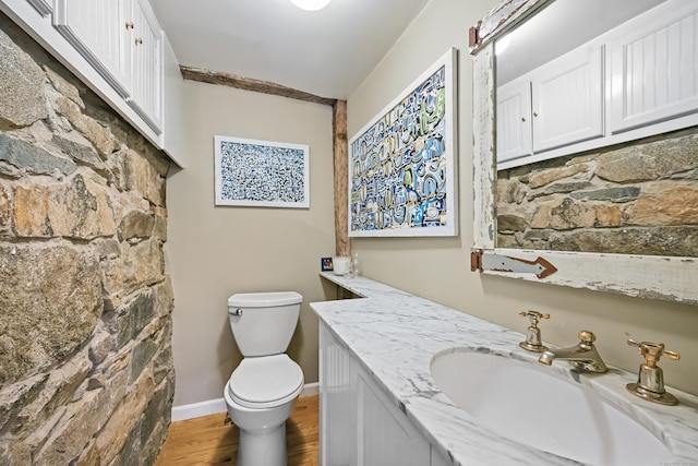 bathroom featuring wood finished floors, toilet, vanity, and baseboards