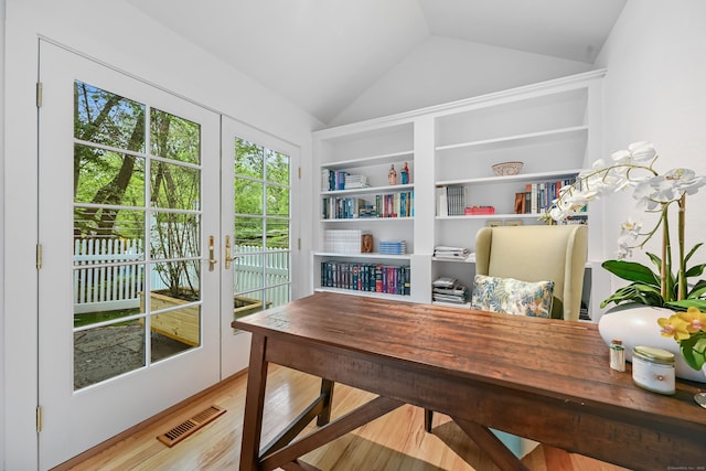 home office featuring lofted ceiling, wood finished floors, and built in features