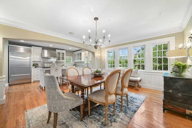 dining room featuring arched walkways, a chandelier, crown molding, light wood-style floors, and recessed lighting
