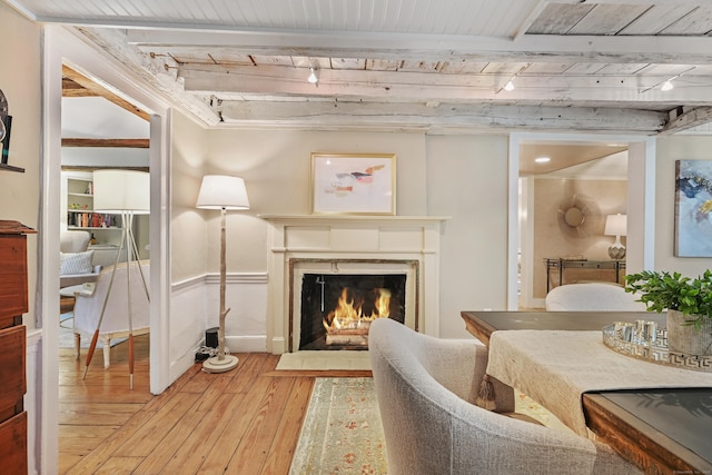 living area with track lighting, light wood finished floors, a premium fireplace, wood ceiling, and beam ceiling