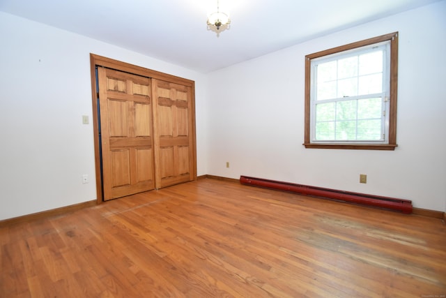 299 Valley Rd, North Branford, CT 06471 - unfurnished bedroom featuring a baseboard heating unit, light wood-type flooring, and baseboards