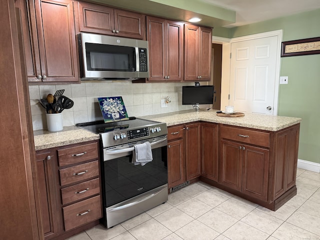 30 May St, Meriden, CT 06451 - kitchen featuring appliances with stainless steel finishes, a peninsula, light tile patterned flooring, tasteful backsplash, and light stone counters