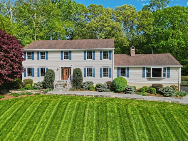 684 Aspen Ln, Orange, CT 06477 - colonial-style house featuring a front yard, a chimney, and a shingled roof