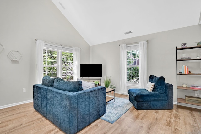 living area with light wood-style floors, healthy amount of natural light, high vaulted ceiling, and baseboards