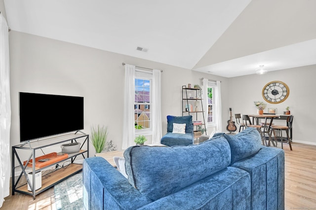 living room featuring light wood-type flooring, lofted ceiling, and baseboards