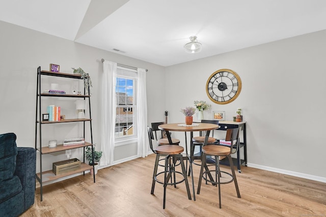 dining space featuring light wood-style flooring and baseboards