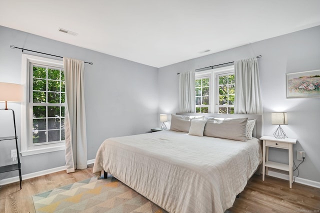 bedroom with wood finished floors, multiple windows, and baseboards