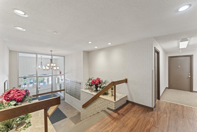 hall featuring wood finished floors, a chandelier, a textured ceiling, recessed lighting, and baseboards
